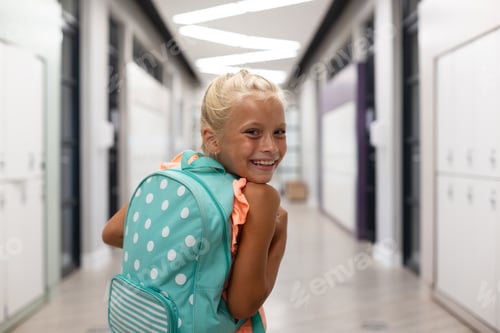 Preview: Portrait of smiling caucasian elementary schoolgirl with backpack looking over shoulder