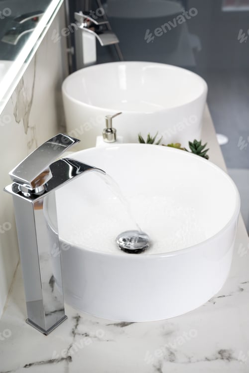 Preview: Pair of ceramic water basins in the interior of light modern bathroom with a mirror with light