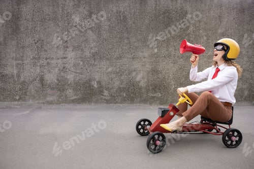 Preview: Funny businesswoman driving retro pedal car outdoor