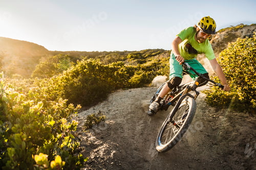 Preview: Cyclist tackling a rugged mountain trail at sunset