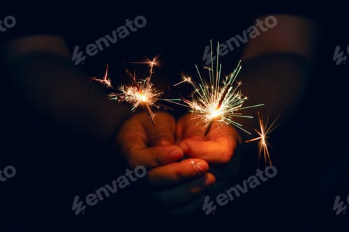 Preview: Woman hand holding a burning sparkler. Christmas and new year sparkler holiday background