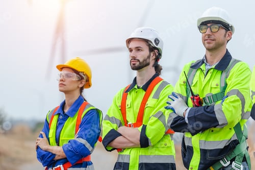 Preview: Teamwork engineer wearing safety uniform standing crossed arms at wind turbine field renewable energ
