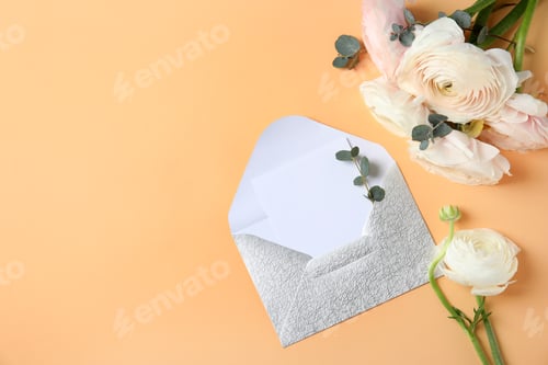 Preview: Flat lay composition with beautiful ranunculus flowers and card in envelope on color background