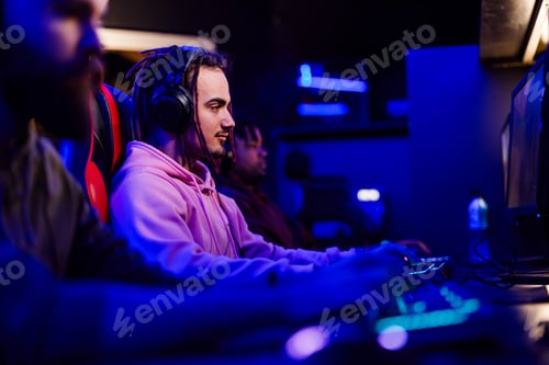 Preview: Side view of gamer with headset playing fps pvp online arena at cybercafe
