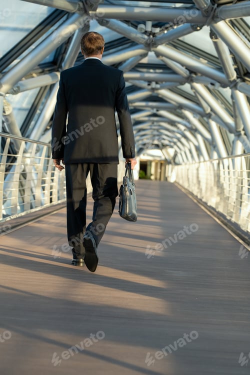 Preview: A man with black leather handbag walking down a long walkway