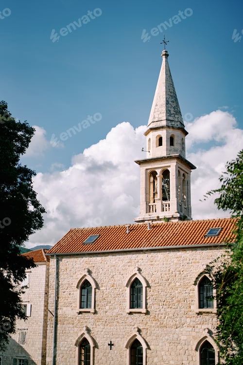 Preview: Tall bell tower of St. John Cathedral against the backdrop of a cloudy sky. Budva, Montenegro