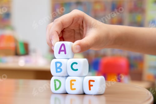 Preview: A child's hand playing with alphabet cube in classroom.