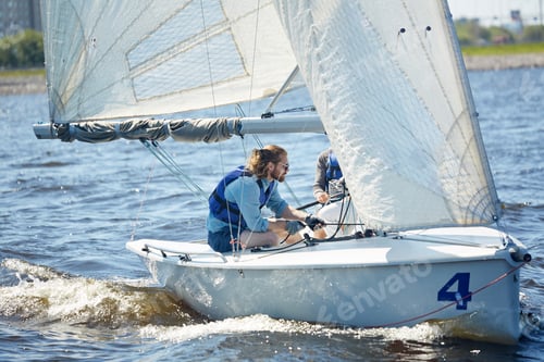 Preview: Handsome man using rope to direct sailboat