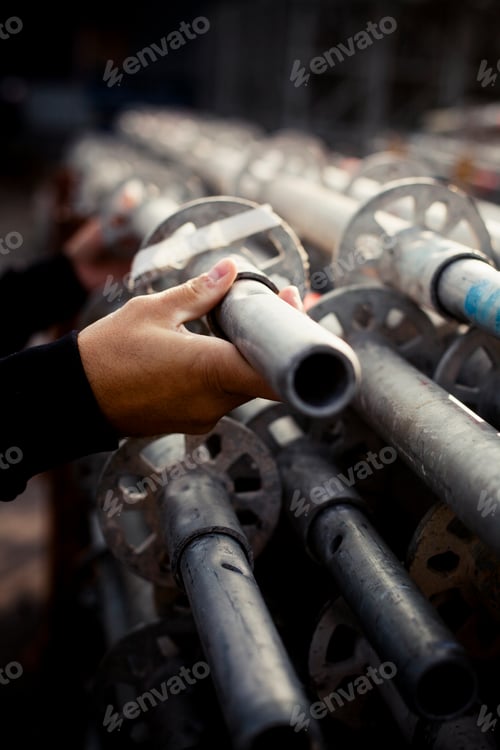 Preview: Cropped image of builder selecting pipe at construction site