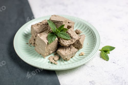 Preview: Pieces of halva on green plate. Sweet dessert with mint leaves on white background