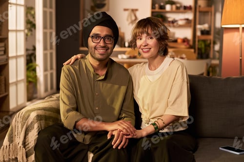 Vista previa: Smiling Couple Sitting on Couch Smiling and Holding Hands