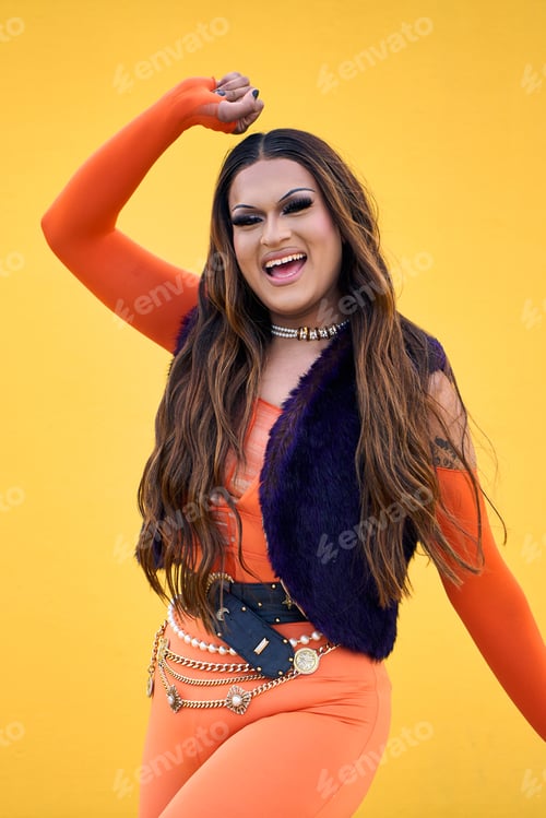 Preview: Portrait of excited transgender young with yellow background. Fun Drag Queen posing for photo.