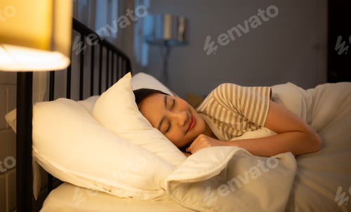 Preview: Asian woman sleeping on the bed in her bedroom at home in the evening