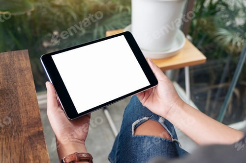 Preview: Mockup image of woman holding black tablet pc with blank white screen while sitting in cafe