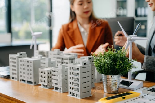 Preview: Team of diverse multiethnic businesspeople standing neare table looking at model of building from