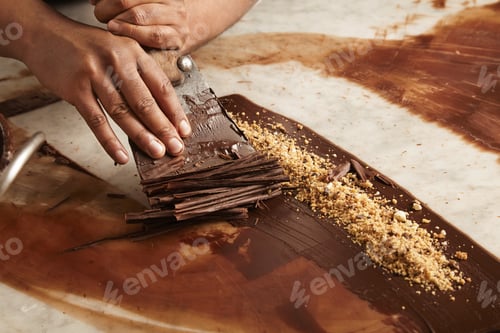 Vorschau: Nahaufnahme eines professionellen schwarzen Mannes, Chef, kocht Kreise aus geschmolzener hausgemachter Schokolade