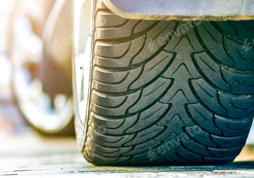 Preview: Close-up detail of car wheel with aluminum disc and black rubber tire protector on light blurred