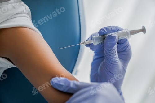 Preview: Close up of doctor's hand ready to injecting patient vaccine with syringe