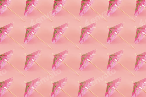 Preview: High angle shot of a pattern with pink cocktail sun umbrellas