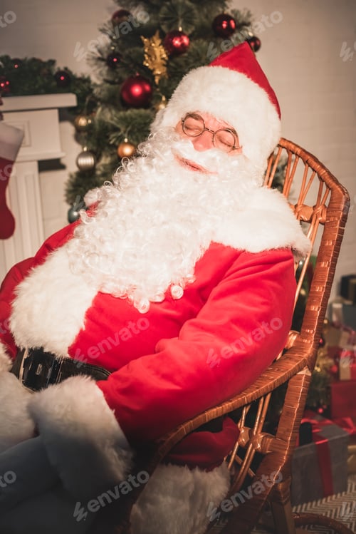 Preview: santa claus sleeping in rocking chair near fireplace and christmas tree