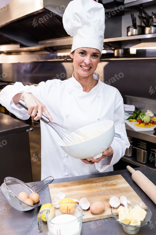 Preview: Chef is whisking batter in mixing bowl in professional kitchen with milk jug, butter and eggshells