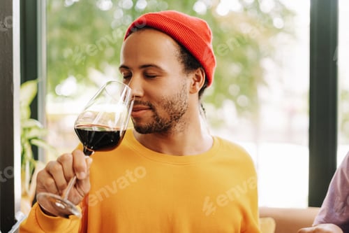 Preview: Young Hispanic man enjoying glass of red wine at restaurant
