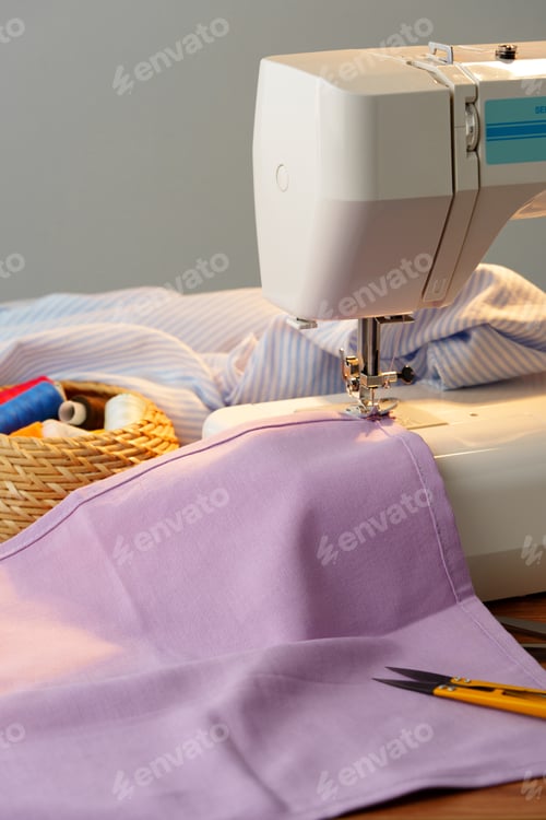 Preview: Sewing machine in use on a wooden table, stitching a light fabric in a well-lit indoor workspace