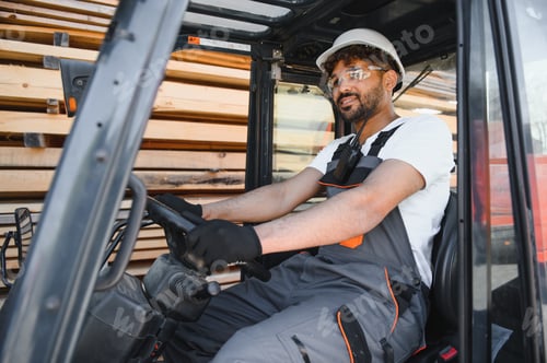 Preview: Warehouse worker driving forklift in lumber yard