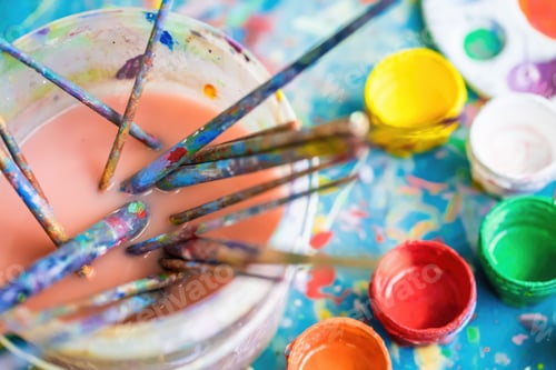 Preview: Colorful paints and used brushes on a messy wooden background