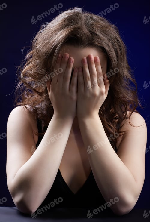 Preview: Portrait Of Beautiful Crying Brunette Girl On Blue Hiding Her Face In Hands