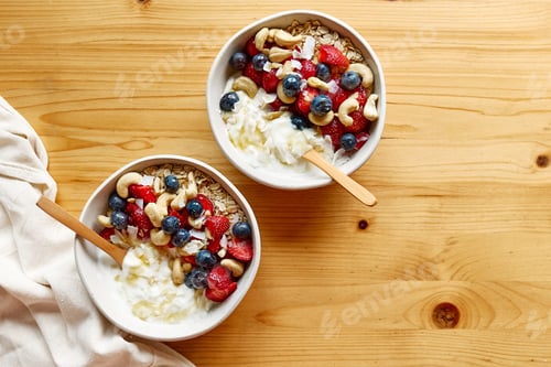 Preview: Coconut yogurt granola with strawberry, blueberry and cashew in white bowl.