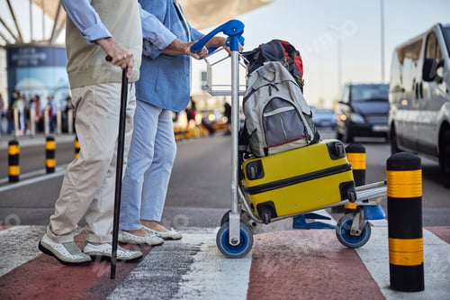 Preview: Senior couple wheeling their baggage cart across the street