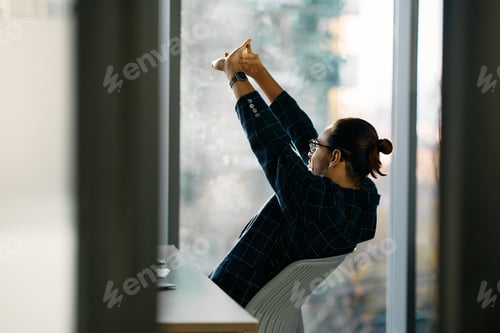 Preview: Male entrepreneur stretching while working in the office and looking through the window.