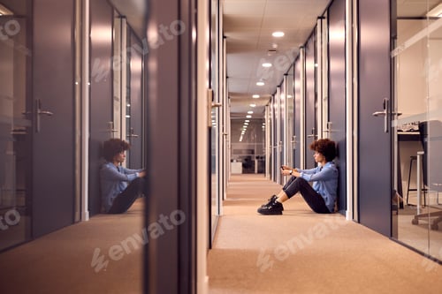 Preview: Stressed Young Businesswoman Sitting On Floor In Corridor Of Modern Office With Phone