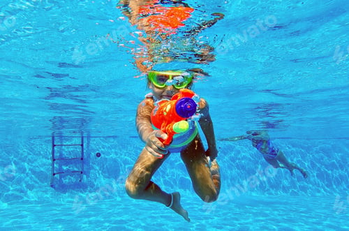Preview: Little Caucasian girl having fun in swimming pool pointed water gun at camera
