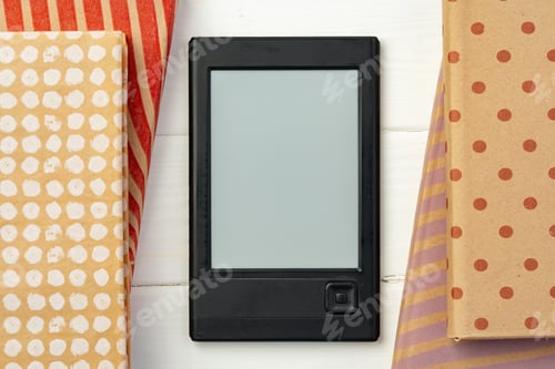 Preview: E-book reader device on background of paper books