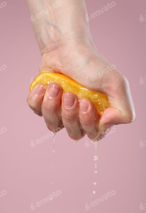 Preview: Woman squeezing orange on pink background, closeup