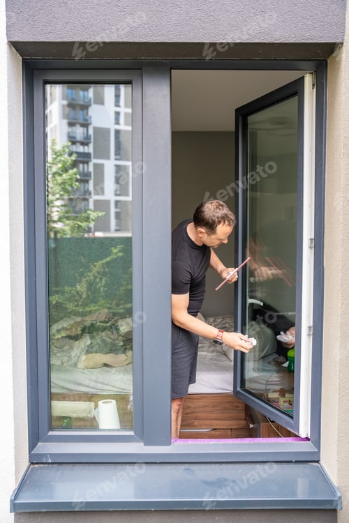 Preview: Young man cleans the windows in the house. He splashes detergent, rubs and removes water at the