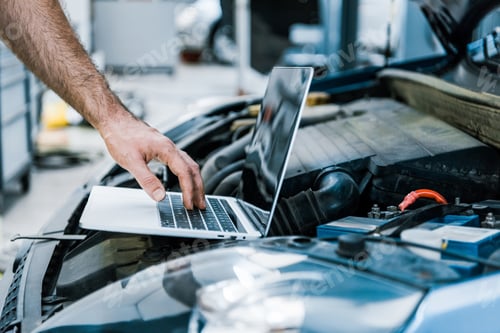Preview: cropped view of auto mechanic using laptop with blank screen near car