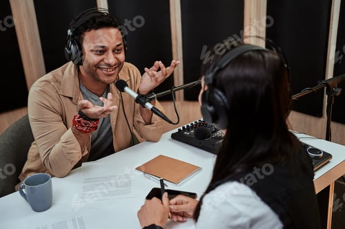 Preview: Portait of happy male radio host smiling, talking to female guest while moderating a live