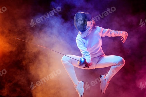 Preview: Teen girl in fencing costume with sword in hand isolated on black background