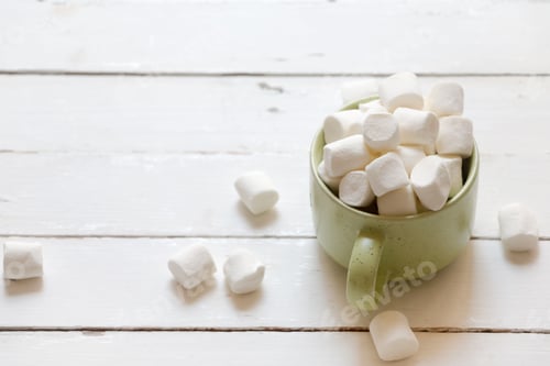 Preview: Marshmallows Overflowing from a Mug on White Wood