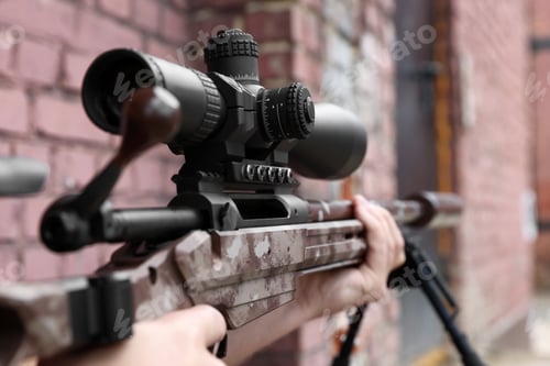 Preview: Soldier holding modern powerful sniper rifle with telescopic sight outdoors, closeup
