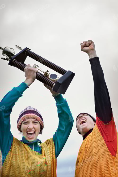Preview: Caucasin woman and man celebrating a team win in a sporting event with a trophy in hand.