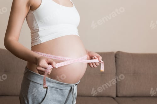Preview: Health well being pregnancy lifestyle. Pregnant woman measuring her belly. Healthy pregnancy.