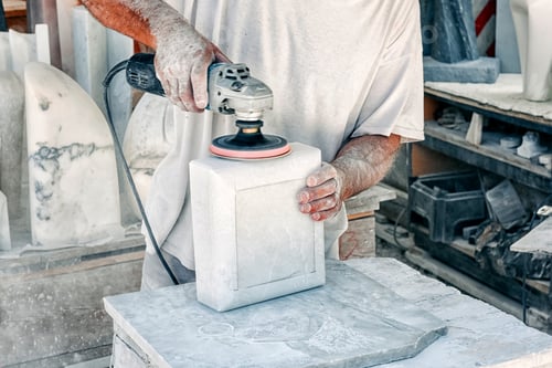 Preview: Man using an orbital sander to smooth a block of marble