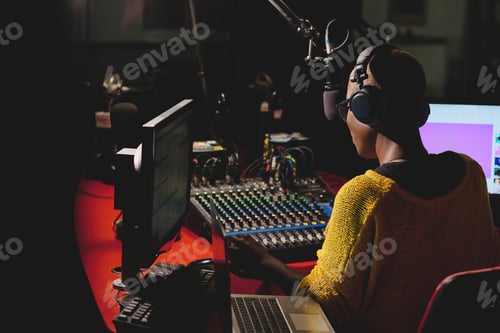 Preview: Black radio host in headphones working in dark studio