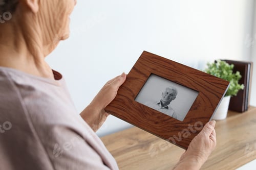 Preview: Elderly woman with framed photo of her son at home