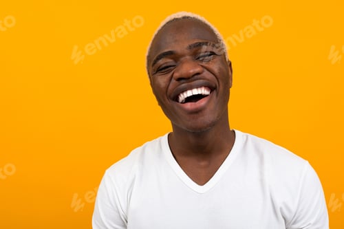 Preview: Closeup portrait of a smiling handsome black blond African man on an orange background with copy