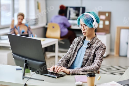 Preview: Man with blue hair using computer in office
